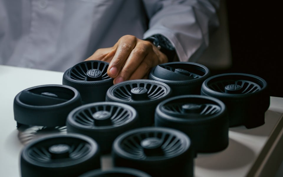 Batch of identical MJF 3D printed nylon parts being inspected for quality, demonstrating medium-volume production capability