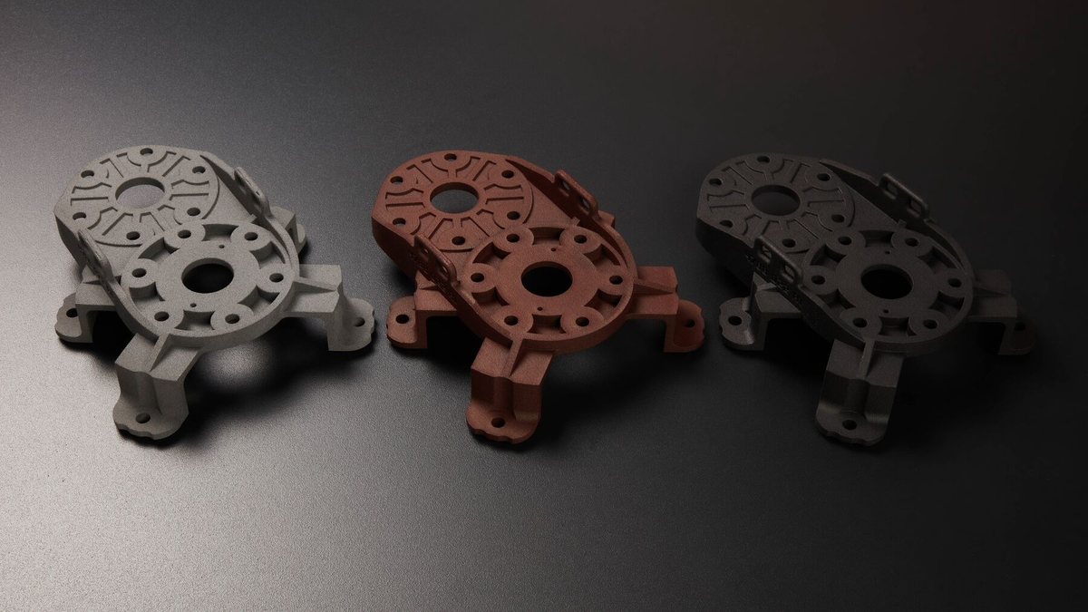 Three identical SLS nylon brackets shown raw gray, dyed dark red, and dyed black